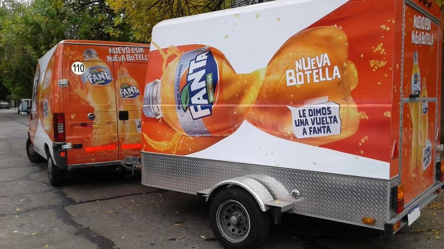 Trailer de OCHO ploteado con la gráfica de una marca de gaseosas, junto a la furgoneta de reparto con la misma campaña