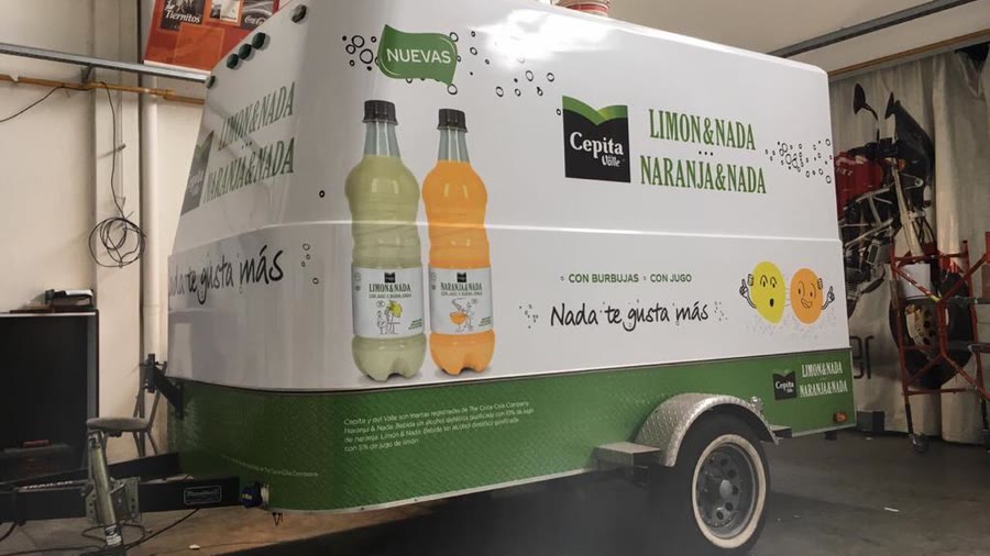 Trailer de OCHO ploteado de punta a punta con la gráfica de una marca de jugos, adentro del taller